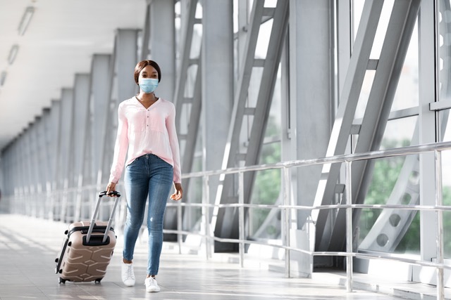 Pandemic Tourism. Young African Female In Medical Mask Walking In Airport Terminal