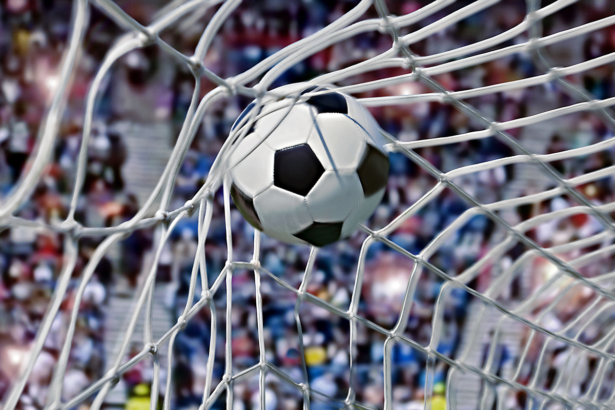 Football, or soccer ball in the back of a net